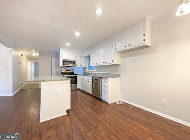 kitchen with a kitchen island, white cabinetry, dark hardwood / wood-style flooring, light stone counters, and stainless steel appliances