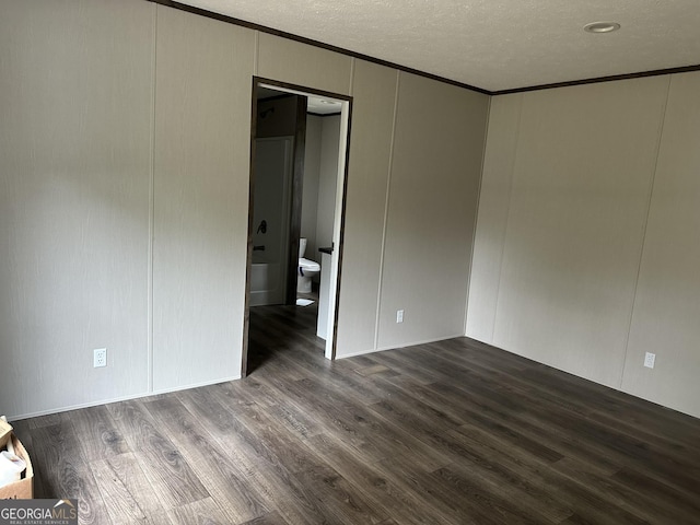 spare room with dark wood-type flooring, crown molding, and a textured ceiling