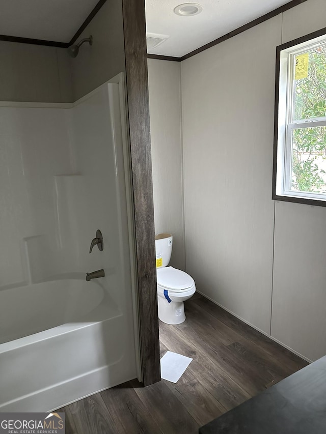 bathroom with wood-type flooring, bathing tub / shower combination, and toilet