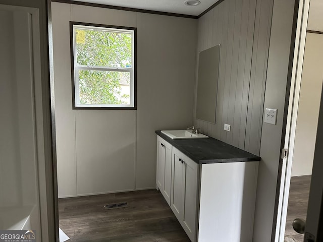 bathroom with ornamental molding, vanity, wooden walls, and wood-type flooring