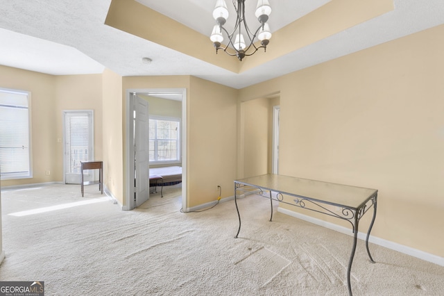 interior space with a raised ceiling, light carpet, and a notable chandelier