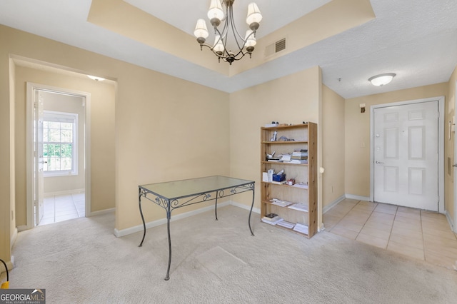 interior space featuring a tray ceiling, a chandelier, light carpet, and a textured ceiling