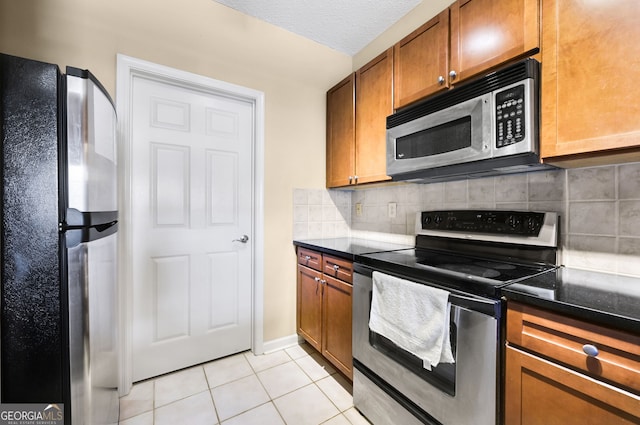 kitchen with tasteful backsplash, stainless steel appliances, a textured ceiling, and light tile patterned flooring