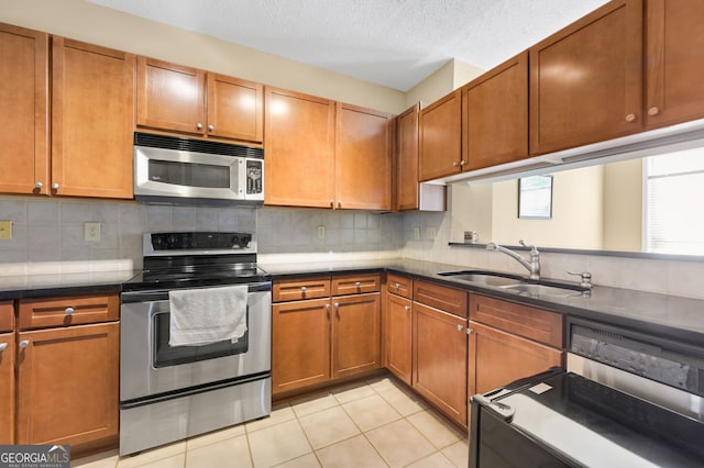 kitchen featuring light tile patterned flooring, sink, tasteful backsplash, a textured ceiling, and stainless steel appliances