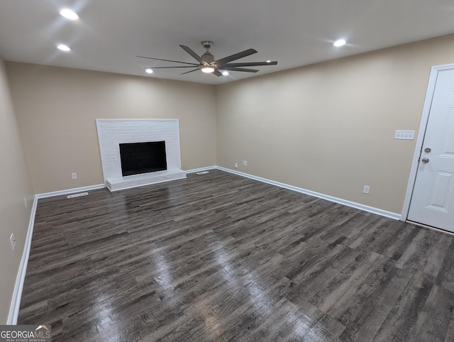 unfurnished living room with dark wood-type flooring, ceiling fan, and a brick fireplace