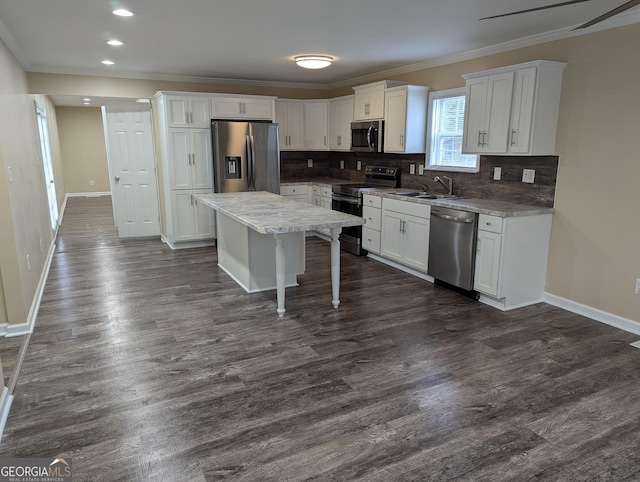 kitchen with stainless steel appliances, sink, a kitchen island, and white cabinets