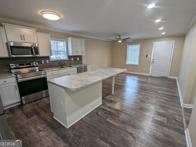 kitchen with white cabinetry, stainless steel appliances, a center island, and sink