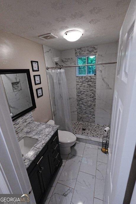 bathroom featuring vanity, toilet, a shower with shower curtain, and a textured ceiling