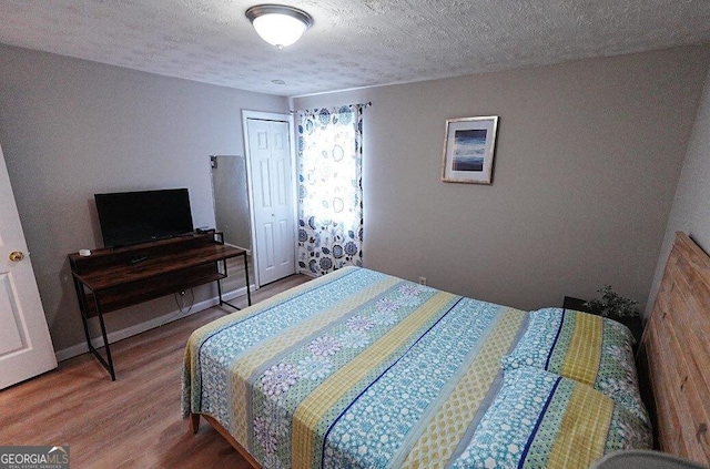 bedroom with hardwood / wood-style flooring, a textured ceiling, and a closet