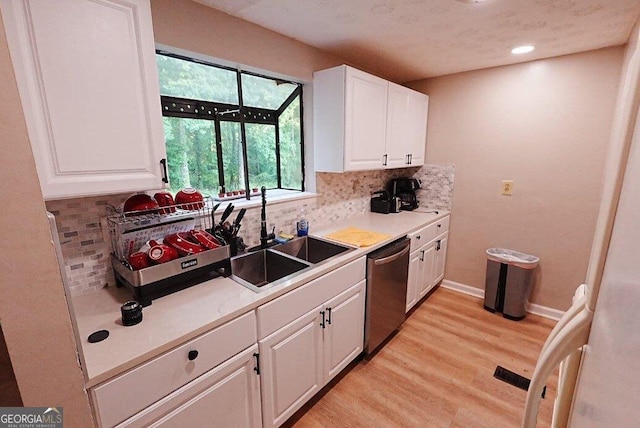 kitchen with tasteful backsplash, sink, stainless steel dishwasher, and white cabinets