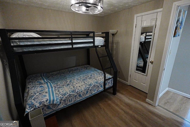 bedroom with an inviting chandelier, hardwood / wood-style floors, and a textured ceiling