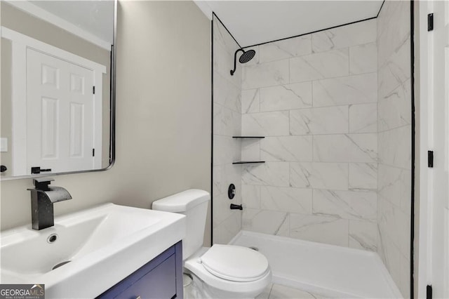 bathroom with vanity, a tile shower, and toilet