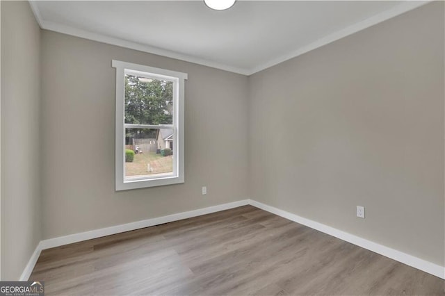 spare room featuring crown molding and light hardwood / wood-style flooring