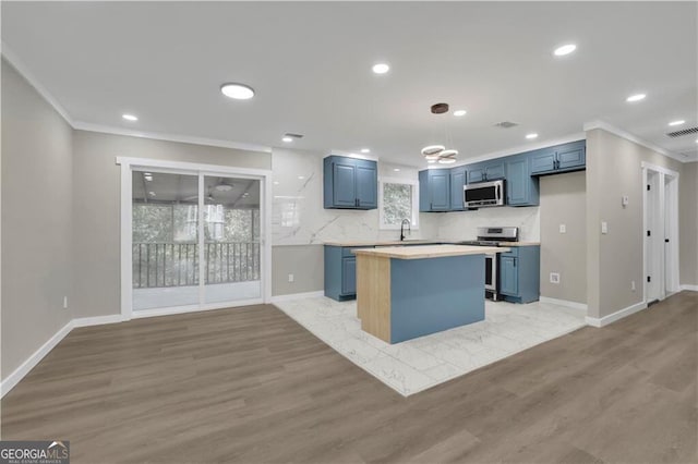 kitchen featuring light hardwood / wood-style flooring, blue cabinetry, appliances with stainless steel finishes, backsplash, and a center island