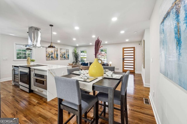 dining room featuring plenty of natural light, beverage cooler, and dark hardwood / wood-style floors