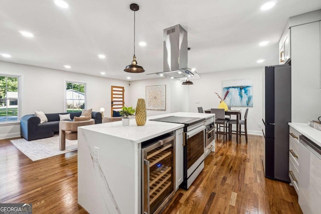 kitchen featuring white cabinetry, hanging light fixtures, stainless steel appliances, wine cooler, and island exhaust hood