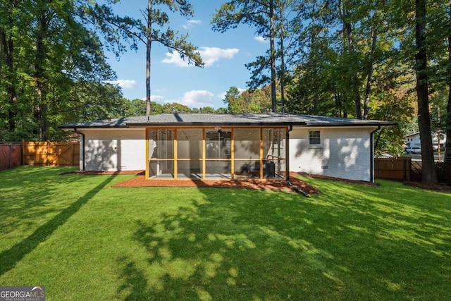 rear view of house featuring a sunroom and a lawn