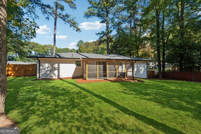 rear view of house with a sunroom and a lawn