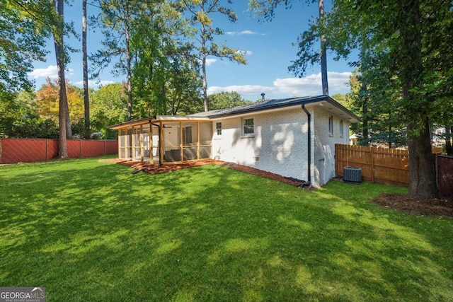 back of property featuring a sunroom, central air condition unit, and a lawn