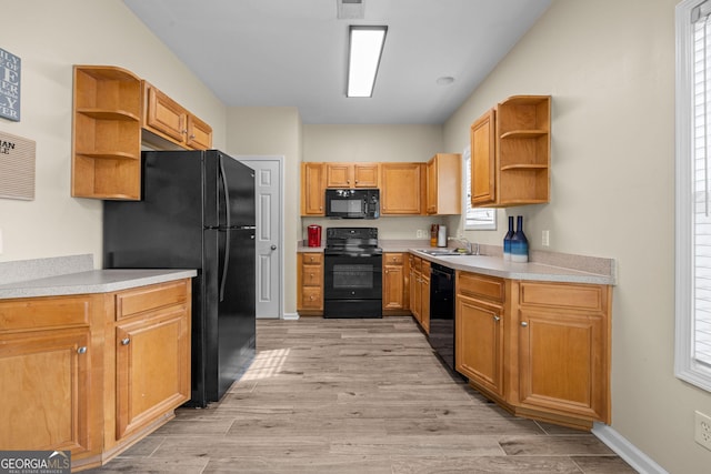 kitchen featuring sink, a wealth of natural light, black appliances, and light hardwood / wood-style floors