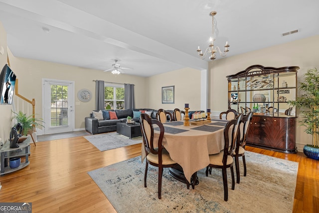 dining area featuring beamed ceiling, ceiling fan with notable chandelier, and light hardwood / wood-style flooring