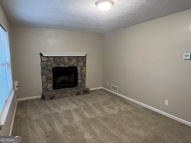 unfurnished living room with a stone fireplace, carpet, and a textured ceiling