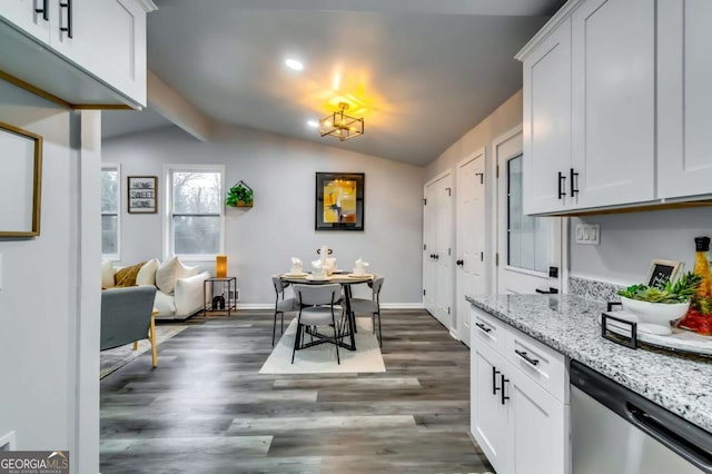 kitchen with white cabinets, vaulted ceiling, light stone countertops, and dishwasher