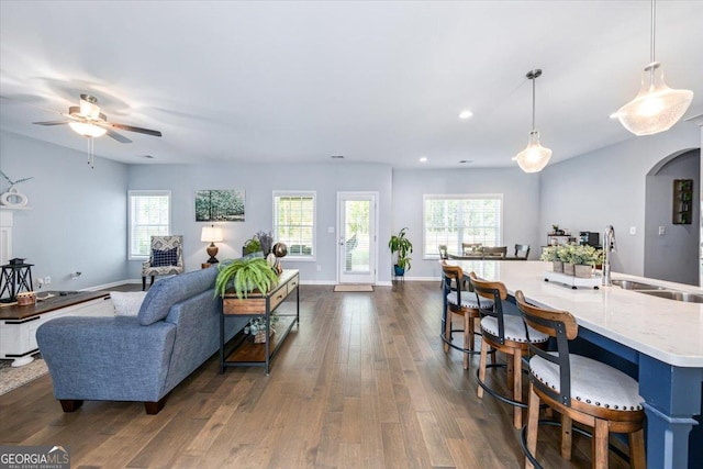 living room with ceiling fan, a healthy amount of sunlight, dark hardwood / wood-style flooring, and sink