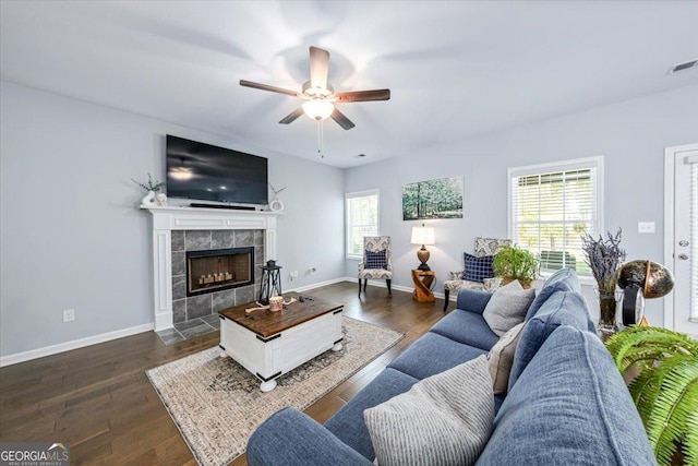 living room with dark wood-type flooring, ceiling fan, and a tile fireplace