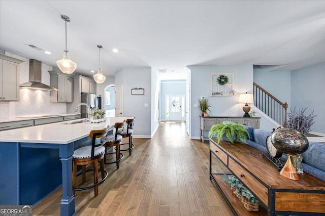 kitchen with wall chimney exhaust hood, sink, gray cabinetry, decorative light fixtures, and decorative backsplash