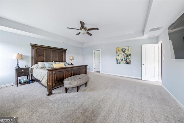 carpeted bedroom with ceiling fan and a tray ceiling