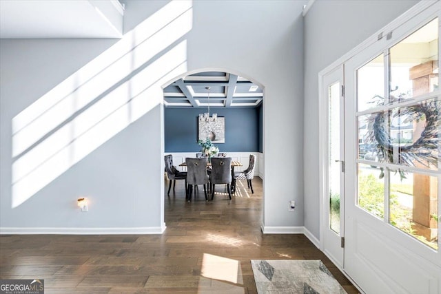 foyer with beamed ceiling, an inviting chandelier, coffered ceiling, and dark wood-type flooring