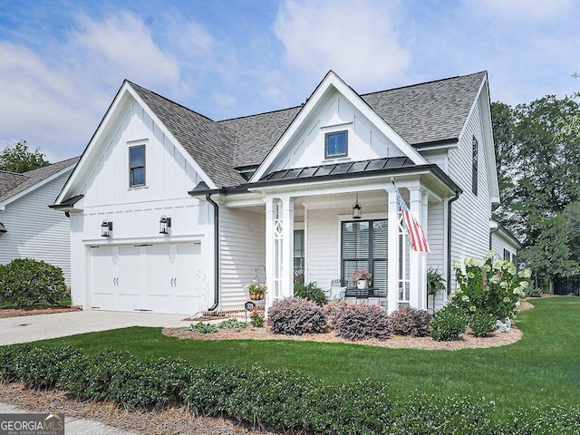 modern inspired farmhouse featuring a garage, covered porch, and a front lawn