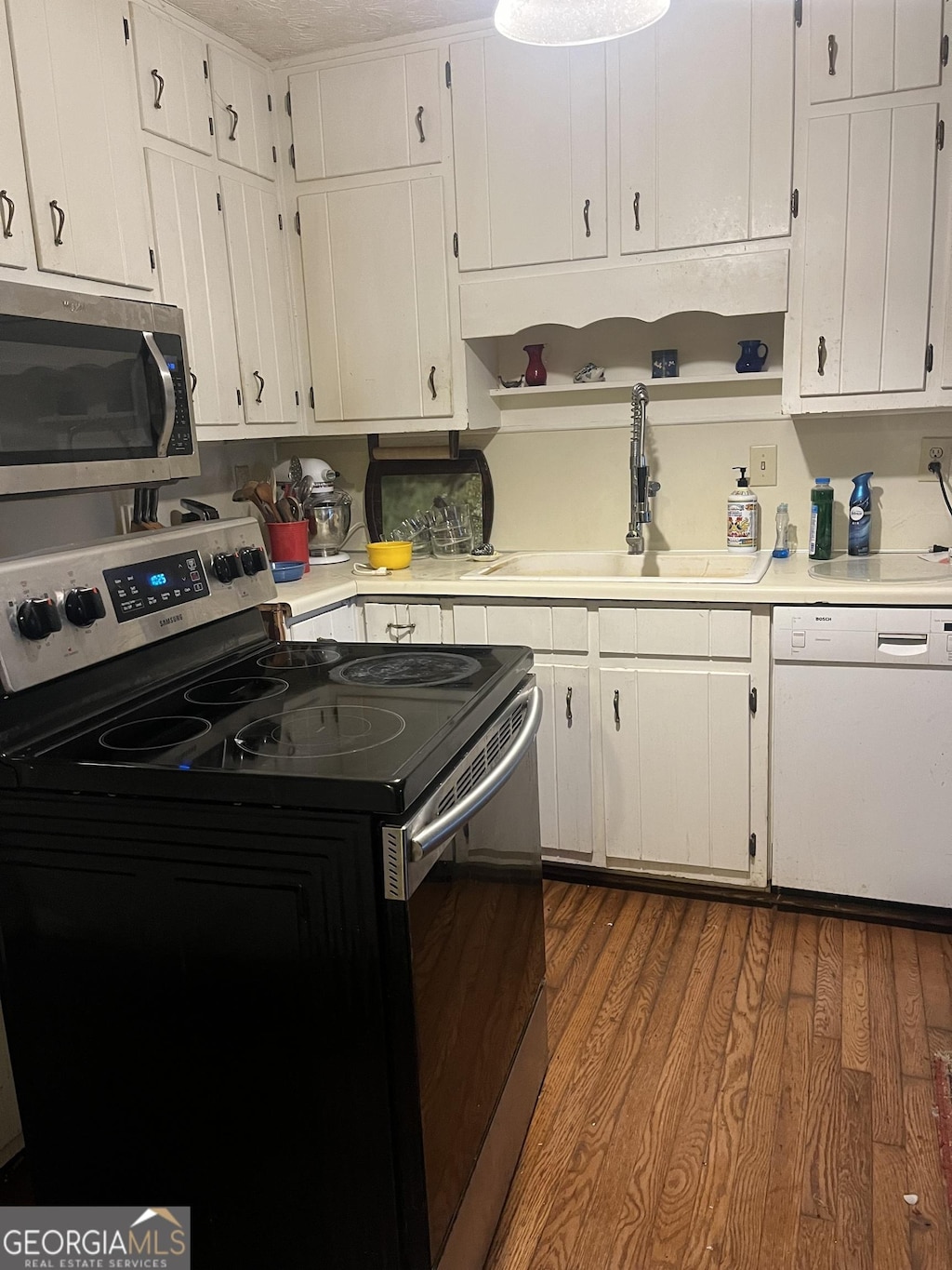 kitchen featuring stainless steel appliances, wood-type flooring, sink, and white cabinets