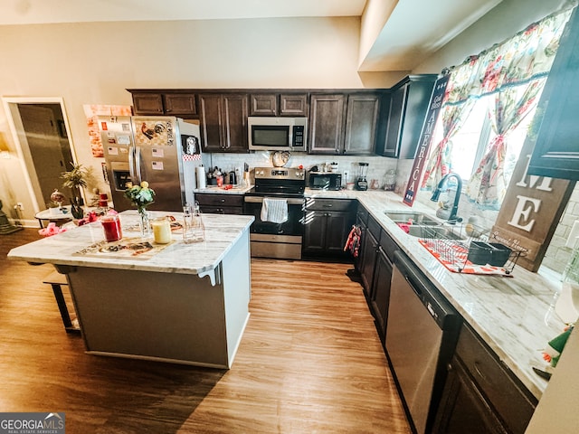 kitchen featuring appliances with stainless steel finishes, a kitchen breakfast bar, a center island, and light hardwood / wood-style floors