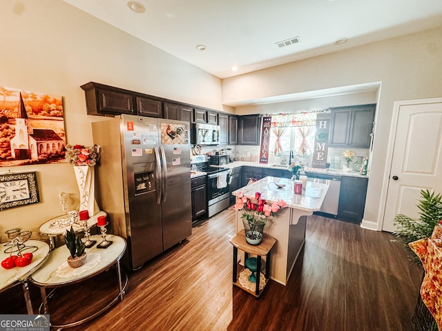 kitchen featuring sink, tasteful backsplash, a kitchen island, hardwood / wood-style flooring, and stainless steel appliances