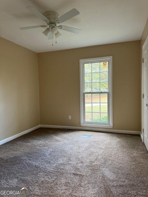 empty room featuring ceiling fan and carpet