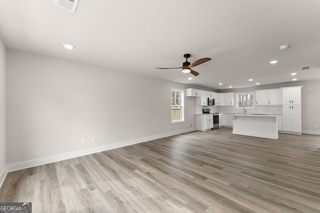 unfurnished living room with baseboards, visible vents, a ceiling fan, light wood-style floors, and recessed lighting