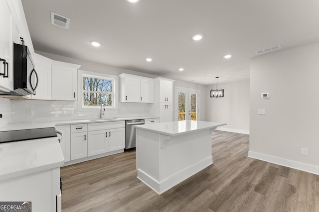 kitchen featuring visible vents, white cabinetry, a kitchen island, a sink, and dishwasher