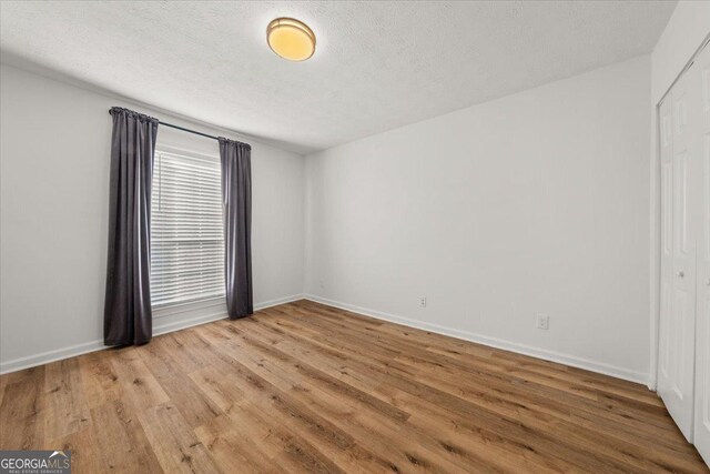 spare room with a textured ceiling and light hardwood / wood-style flooring