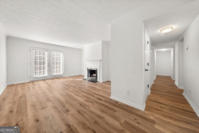 unfurnished living room featuring french doors, a textured ceiling, and light hardwood / wood-style flooring