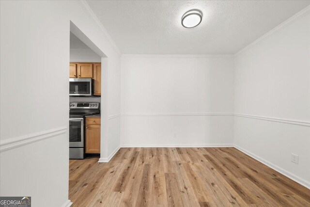 kitchen featuring crown molding, appliances with stainless steel finishes, a textured ceiling, and light hardwood / wood-style flooring