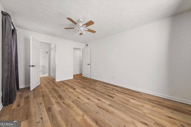 unfurnished bedroom with ensuite bathroom, ceiling fan, a textured ceiling, and light hardwood / wood-style floors