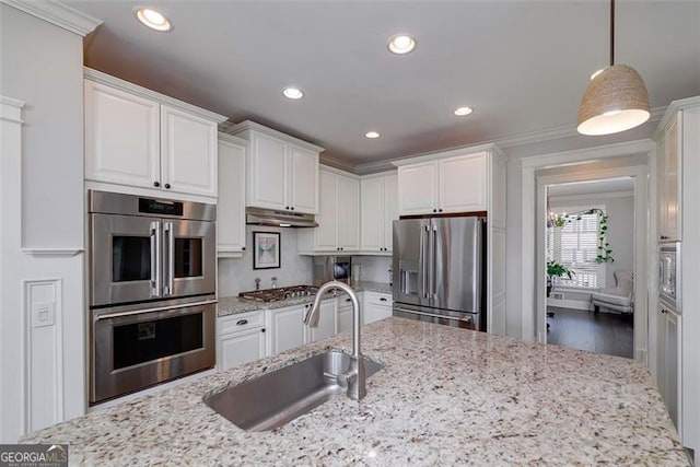 kitchen featuring stainless steel appliances, hanging light fixtures, sink, and white cabinets