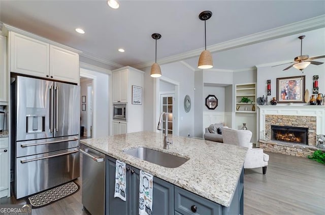 kitchen featuring sink, white cabinetry, stainless steel appliances, ornamental molding, and built in shelves