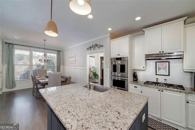 kitchen featuring stainless steel appliances, an island with sink, ornamental molding, and white cabinets