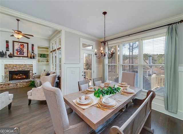 dining area featuring crown molding, dark hardwood / wood-style flooring, built in shelves, and a stone fireplace