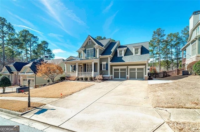 view of front of property featuring concrete driveway, an attached garage, fence, and covered porch