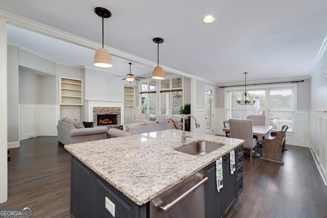 living room featuring dark wood-type flooring, a stone fireplace, ornamental molding, built in features, and ceiling fan