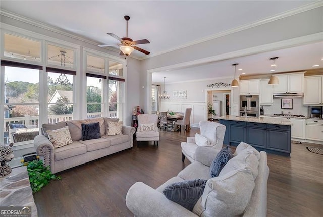 living room with sink, dark wood-type flooring, ornamental molding, and ceiling fan